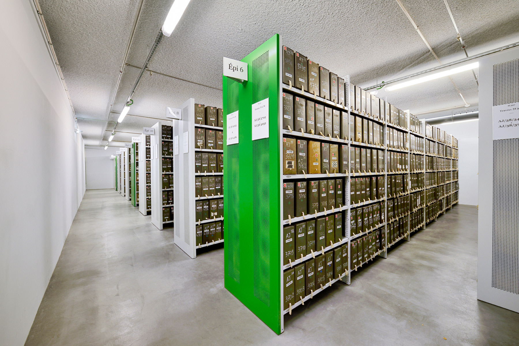 Fachbodenregale in einem Archiv, das Archivregal im Vordergrund hat eine grüne Vorsatzwand